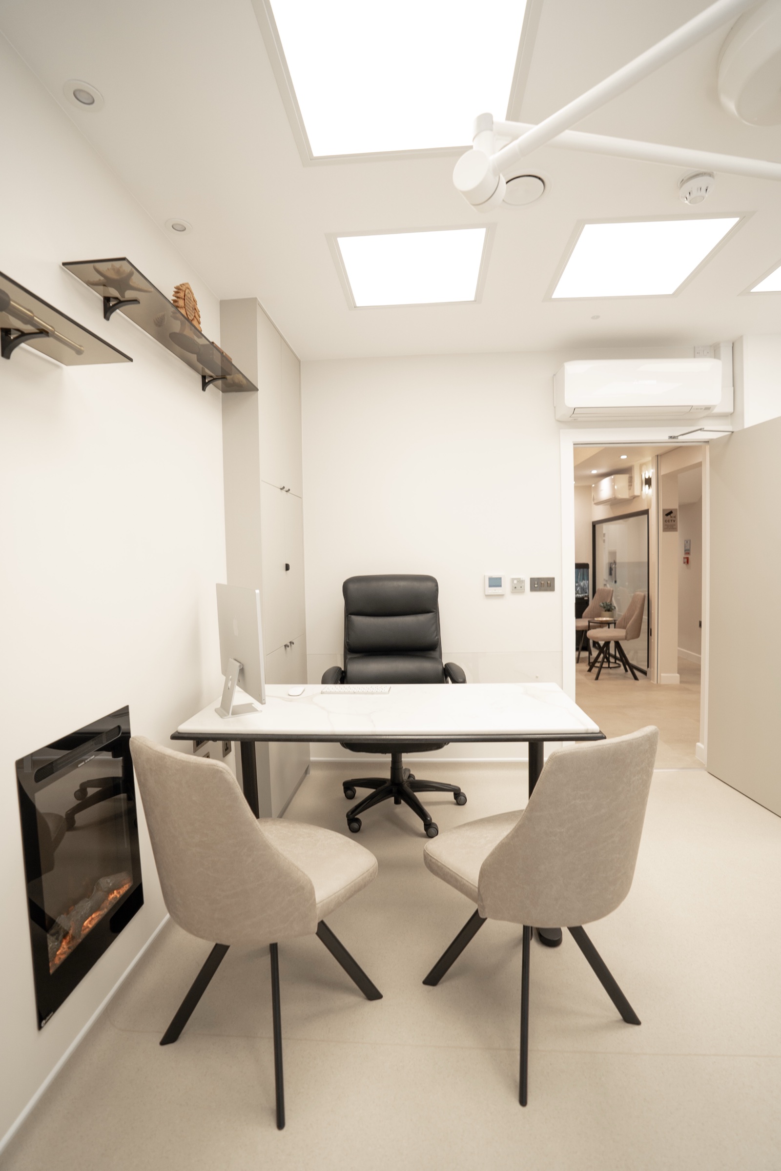 Consultation room at Kensington Cosmetic Clinic with marble desk and electric fireplace